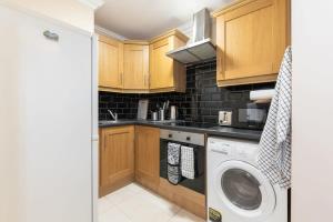 a kitchen with wooden cabinets and a washer and dryer at Central 1BED APT RELIABLE FAST WIFI & TV in Dublin