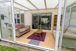 a glass house with a couch and a table at 5 bed house, cntrl bmouth, free parking, garden - Talbot House in Bournemouth