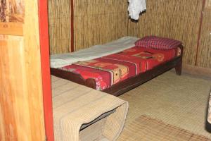 a small room with a bed and a table at Red Rocks Rwanda - Bamboo Cottage in Nyakinama
