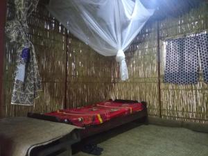 a room with a bed in a straw hut at Red Rocks Rwanda - Bamboo Cottage in Nyakinama