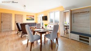 jadalnia i salon ze stołem i krzesłami w obiekcie Wonder Home - Apartament Górska Panorama z widokiem na uzdrowisko i Góry Izerskie w Świeradowie Zdroju