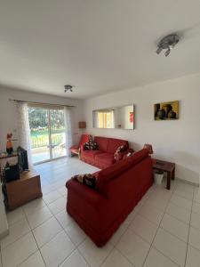 een woonkamer met twee rode banken en een tv bij Iris Village Grand Apartment in Paphos City