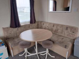 a wooden bench with a table and two stools at Foleys Cabin - Cosy retreat in Winchelsea