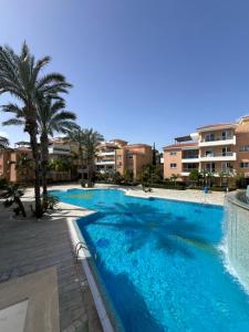 een groot blauw zwembad met palmbomen en gebouwen bij Iris Village Grand Apartment in Paphos City