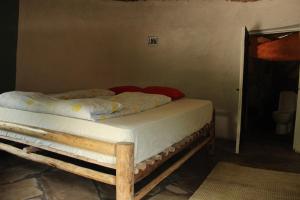 a bed in a room with a wooden frame at Red Rocks Rwanda - Campsite Guesthouse in Nyakinama