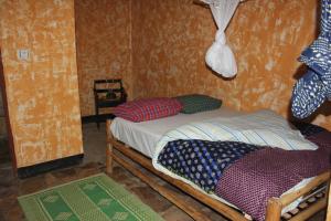 a small room with a small bed with pillows on it at Red Rocks Rwanda - Campsite Guesthouse in Nyakinama