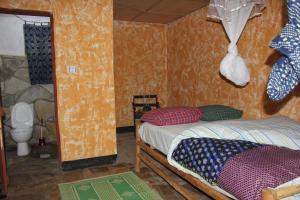 a small room with a bed and a toilet at Red Rocks Rwanda - Campsite Guesthouse in Nyakinama