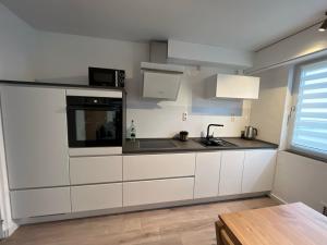 a kitchen with white cabinets and a sink and a microwave at Ferienwohnung Wendel in Sankt Wendel