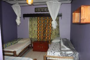 Cette chambre comprend deux lits et un mur avec des rideaux. dans l'établissement Room in BB - Amahoro Guest House - Triple Room with Shared Bathroom, à Ruhengeri