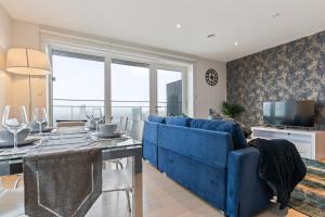 ein Wohnzimmer mit einer blauen Couch und einem Fernseher in der Unterkunft Elegant 2BR flat on 20th floor near many attractions in London