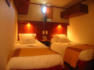 Habitación de hotel con 2 camas y una luz en la pared en Bateau Le Phénicien, en Aigues-Mortes