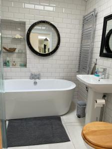 a white bathroom with a tub and a sink at Teal Cottage, Killlyleagh in Killyleagh