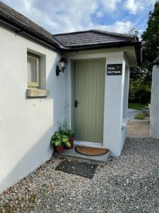 a white house with a green door with two plants at Teal Cottage, Killlyleagh in Killyleagh