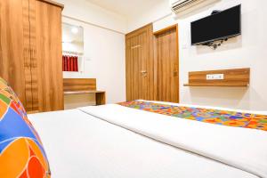 a bedroom with a bed and a flat screen tv at FabHotel Candor Amigo in Navi Mumbai