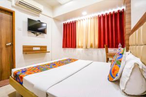 una camera d'albergo con letto e TV di FabHotel Candor Amigo a Navi Mumbai