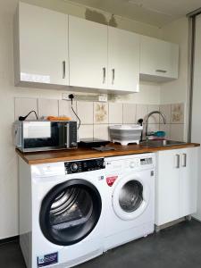 eine Küche mit einer Waschmaschine und einer Mikrowelle in der Unterkunft Dedicated Bedroom & Bathroom in Billund near Lego House & Legoland in Billund