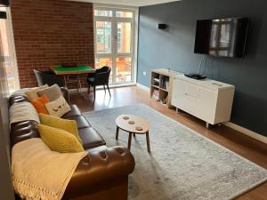 a living room with a leather couch and a table at Modern Stylish Apartments and Rooms at Student Roost Corner House in Sheffield in Sheffield