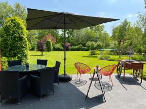 un patio con mesa, sillas y sombrilla en B&B 't Landschap, en Boelenslaan