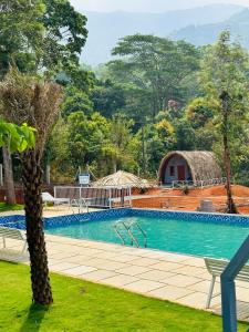 a swimming pool with a palm tree and a building at Historic Heaven wayanad in Vythiri