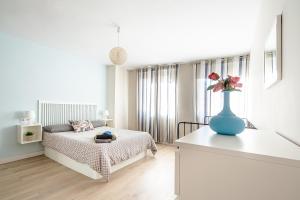 sypialnia z łóżkiem i wazonem z kwiatami na stole w obiekcie CARTAGENAFLATS, Apartamentos Anfiteatro Romano w mieście Cartagena