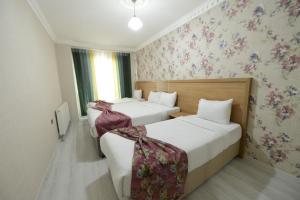 duas camas num quarto de hotel com papel de parede floral em ADA LİFE SUİT HOTEL VAN em Bostaniçi