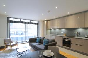 a kitchen and living room with a couch and a table at Barons Court Queens Club by Viridian Apartments in London