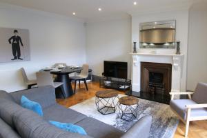 a living room with a couch and a table at Barons Court Queens Club by Viridian Apartments in London