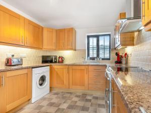 a kitchen with wooden cabinets and a washer and dryer at The Shippon in Halwill