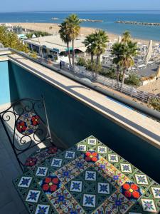 una panchina su un balcone con vista sulla spiaggia di Appartamento Fronte Mare a Civitanova Marche