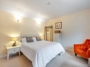 a bedroom with a white bed and a orange chair at The Shippon in Halwill