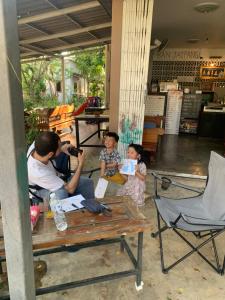 un hombre y dos niños sentados en una mesa de picnic en ใจแปงโฮมสเตย์ Jaipang Homestay, en Pai