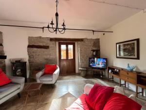 a living room with a couch and a tv at Villa delle Fonti - Villa with pool in Toano