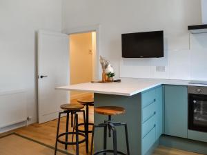 艾爾的住宿－Main Street Flat B - Uk46449，厨房配有蓝色橱柜和带凳子的台面