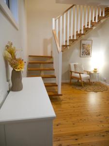 een woonkamer met een trap en een vaas met bloemen bij Luxury Home in Yowie Bay in Miranda