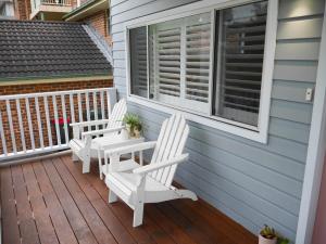 twee witte stoelen op de veranda van een huis bij Luxury Home in Yowie Bay in Miranda