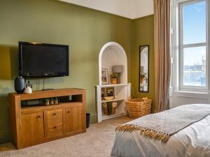 a bedroom with a flat screen tv on a green wall at Main Street Flat B - Uk46449 in Ayr