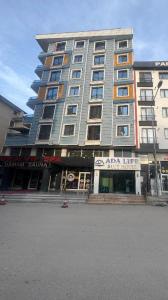 duży wysoki budynek z sklepem przed nim w obiekcie ADA LİFE SUİT HOTEL VAN w mieście Bostaniçi