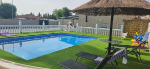 a swimming pool with two chairs and an umbrella at chalet El campillo in Seville