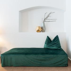 a bedroom with a green bed with a pillow at Hotel Forstinger - Boutique Hotel Schärding in Schärding