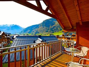 a balcony with a table and chairs and mountains at Modern Mountain Penthouse - an der Skipiste in Rauris