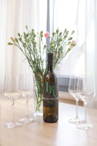 una bottiglia di vino seduta accanto a tre bicchieri di vino di Kamena kuća a Požega