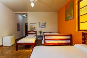 a room with three beds with orange walls at Pousada Recanto da Ladeira in Paraty
