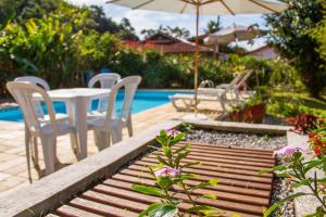 un patio con mesa y sillas junto a una piscina en Pousada Recanto da Ladeira, en Paraty