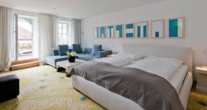 een slaapkamer met 2 bedden en een woonkamer met blauwe stoelen bij Hotel Forstinger - Boutique Hotel Schärding in Schärding