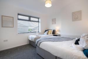 two beds in a room with white walls and a window at Modern - 2 Bed - Free Parking in Coxhoe