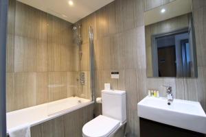 a bathroom with a toilet and a sink and a tub at Barons Court Queens Club by Viridian Apartments in London