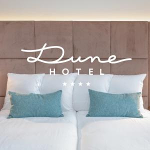 a hotel sign above a bed with pillows at Dune Hotel Nieuwpoort in Nieuwpoort