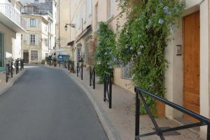 an empty street with flowers on the side of a building at Arles Forum - Les Pénitents Bleus in Arles