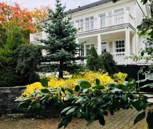 una casa blanca con un árbol y flores amarillas en White House, en Kokkola