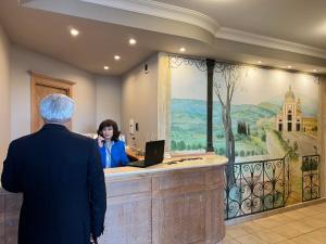 un homme et une femme debout à un comptoir avec un ordinateur portable dans l'établissement Hotel Cladan, à Assise